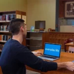 A student studying on a laptop in a library.