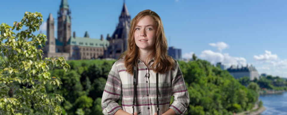 A girl holding a camera in front of Canadian Parliament buildings in Ottawa