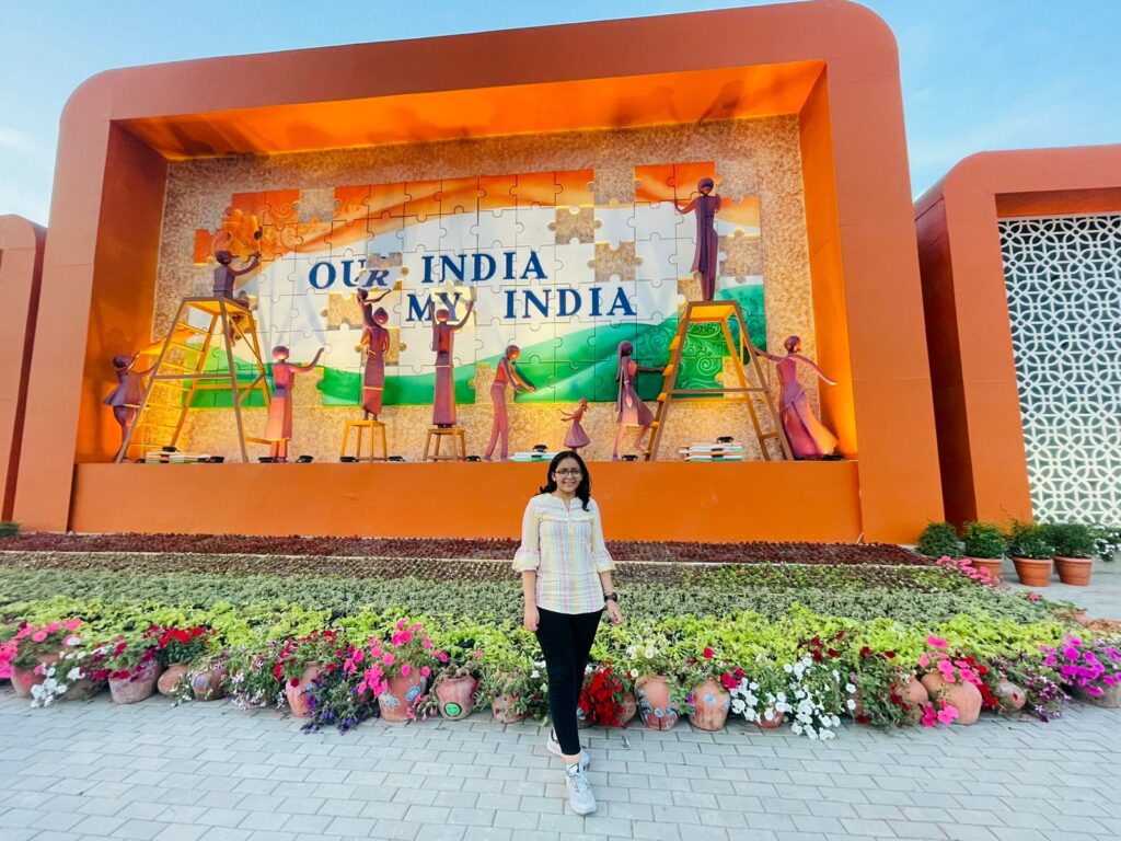A woman standing in front of a building with a sign that says one india.
