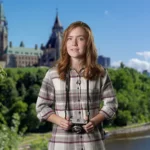 A girl holding a camera in front of Canadian Parliament buildings in Ottawa