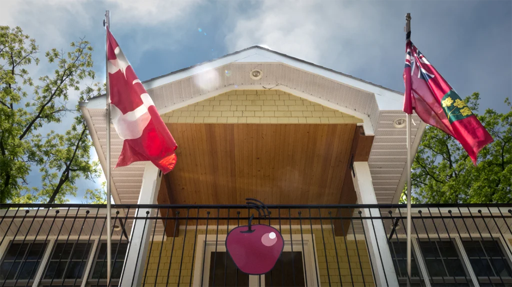 The virtual high school apple logo, and Canadian and Ontario flags flying from the balcony of the administrative office.