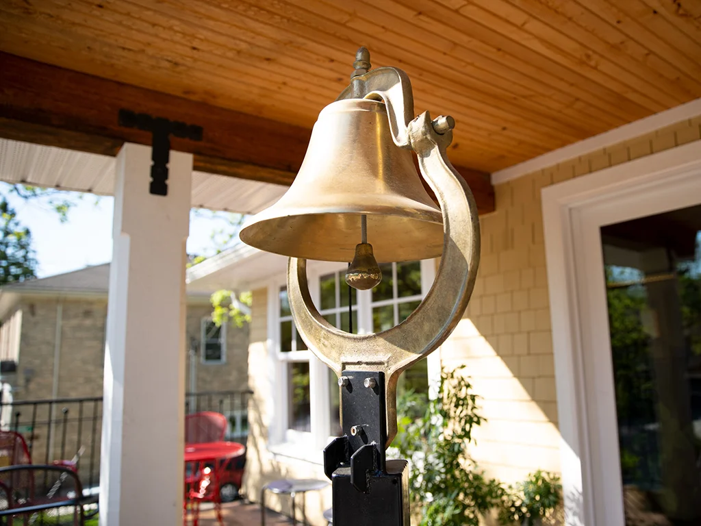 A brass school bell hanging on the front balcony of the Virtual High School administrative office.