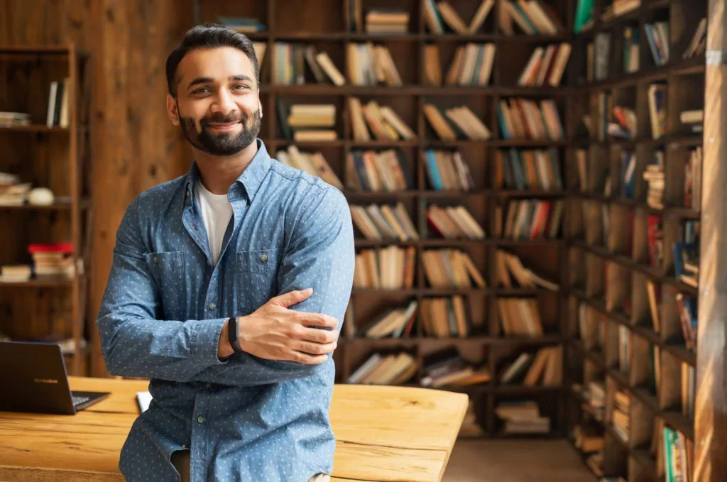 A man standing in front of a bookcase in a library.