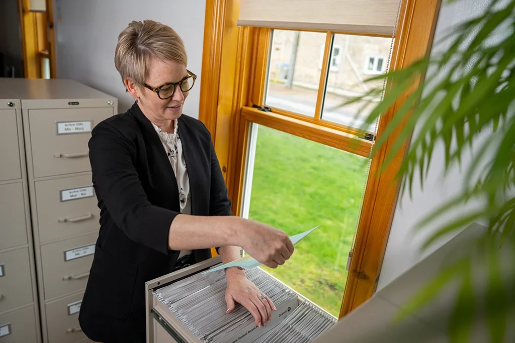 A school administrator pulling out a file from within a filing cabinet.