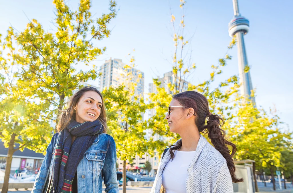 Two friends talking in front of the cn tower in toronto.