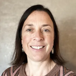 A woman in a brown sweater smiles for the camera.