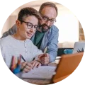 A man and a boy working on a laptop.