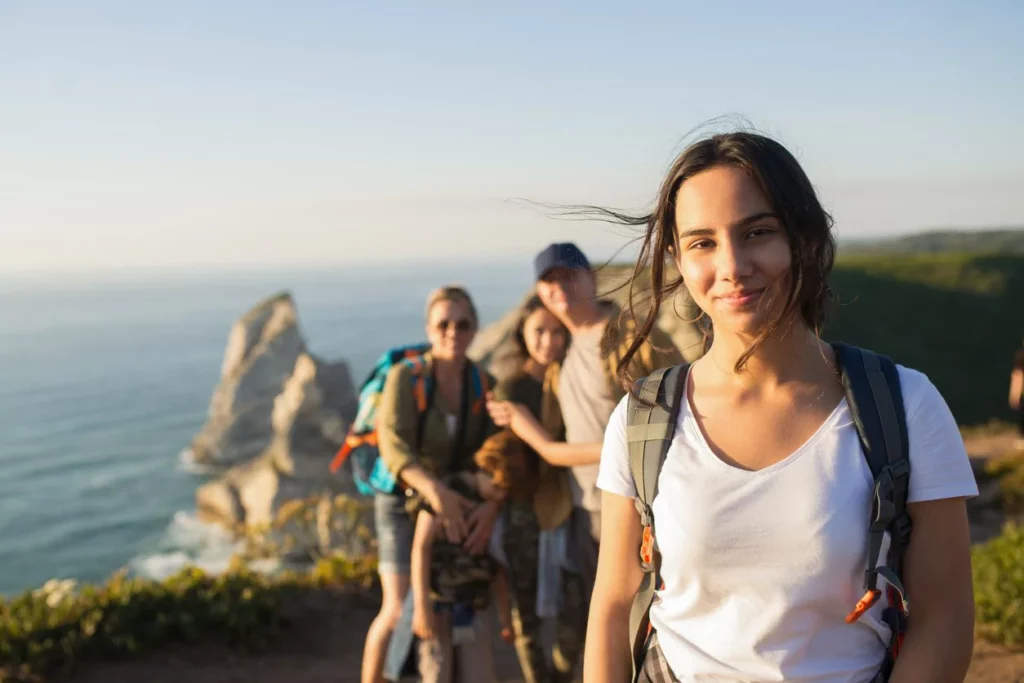 A student on vacation with her family, hiking on a cliff overlooking the ocean.