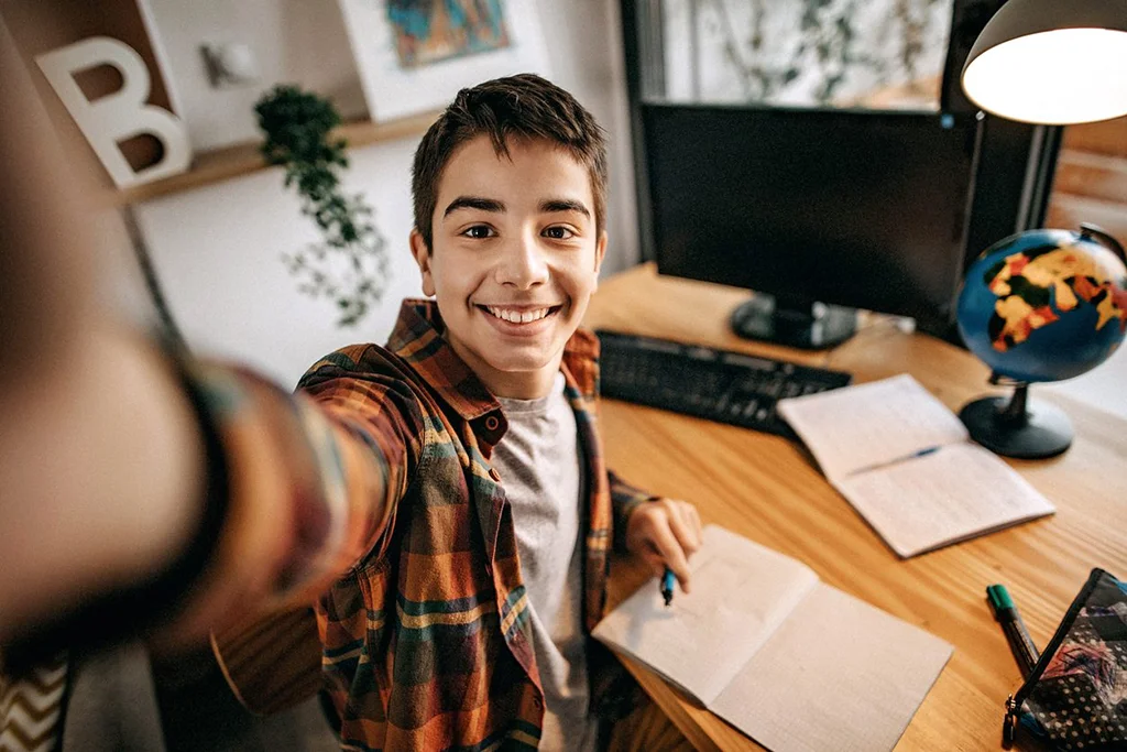A young man taking a selfie at his desk.