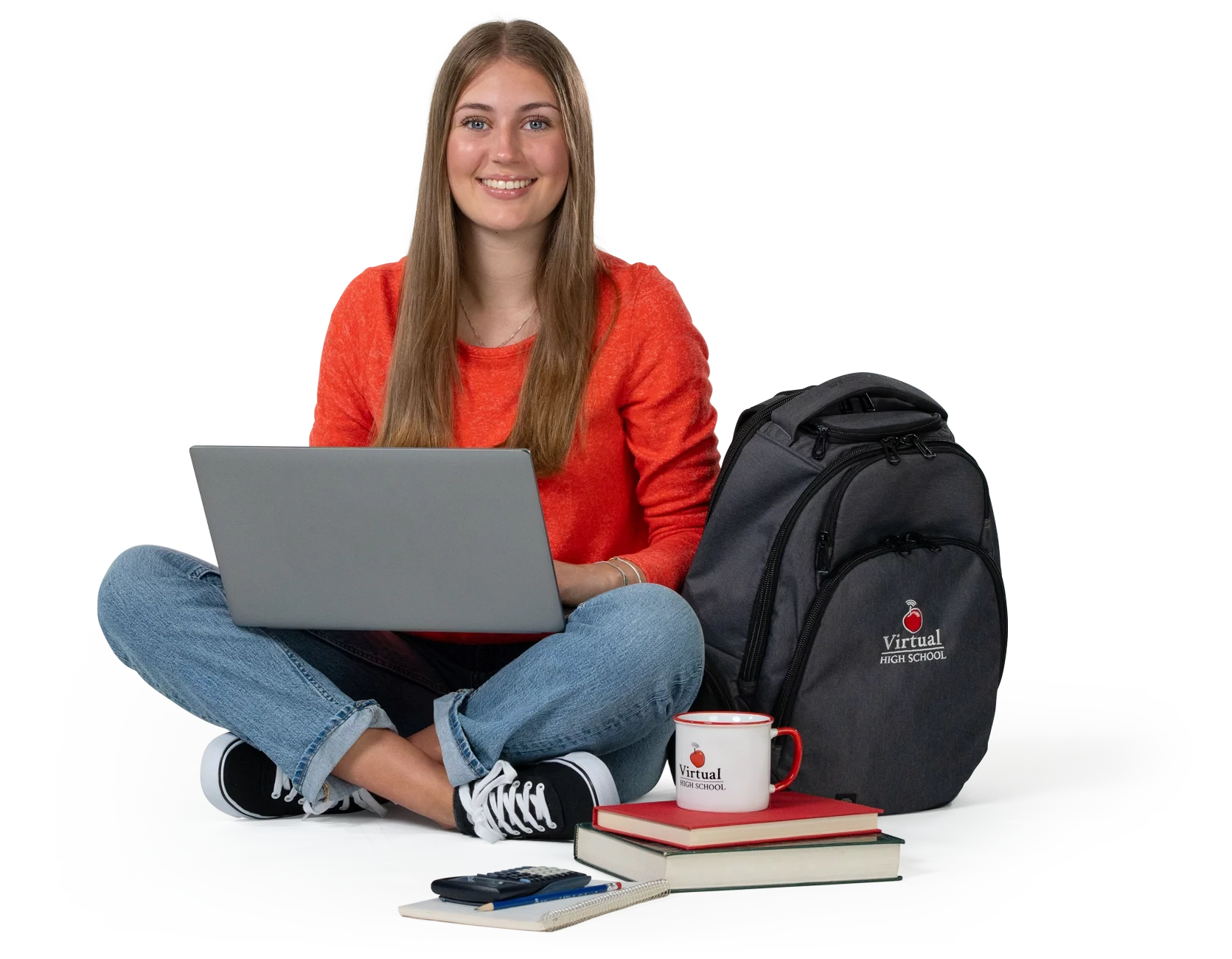 Smiling young lady sitting cross-legged with a laptop, books, and coffee cup.